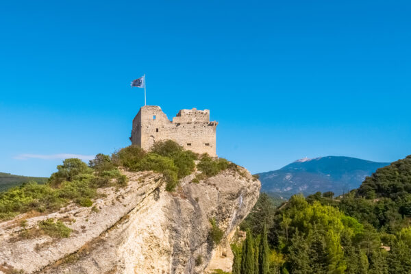 Vue lointaine du château médiéval de Vaison-la-Romaine perché sur un éperon rocheux.