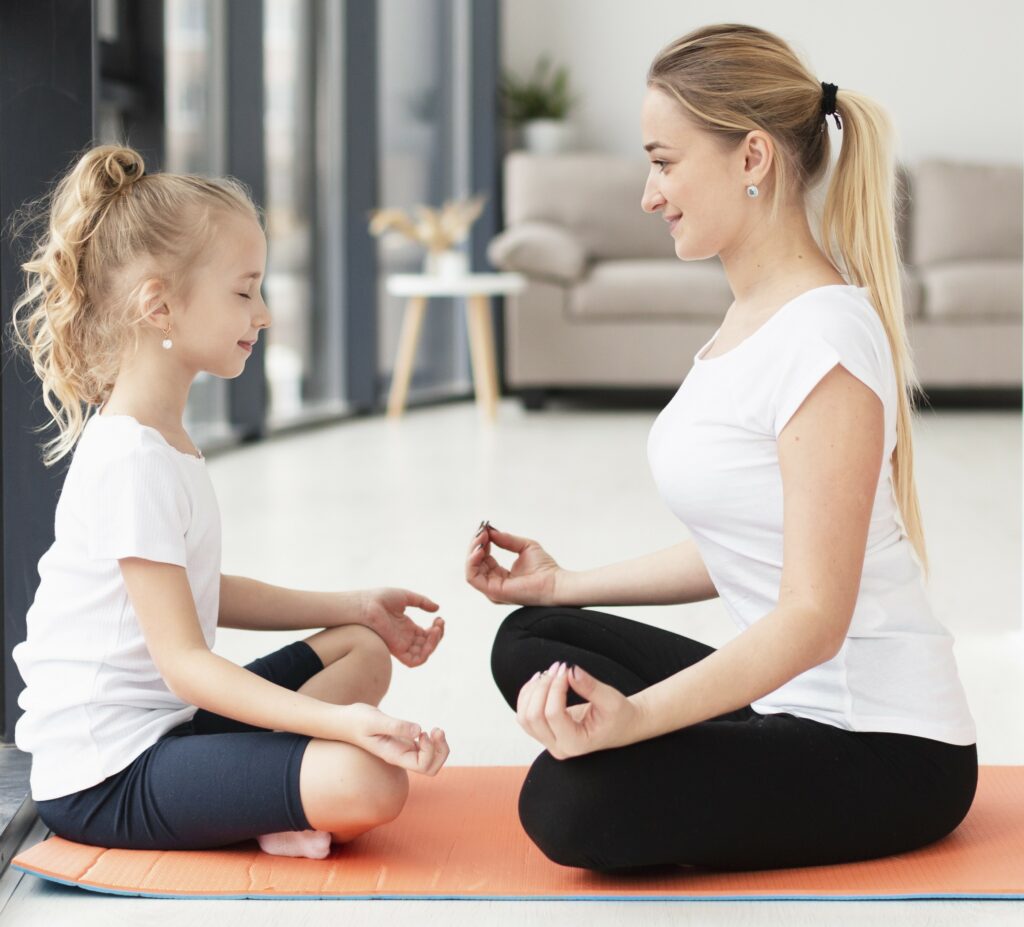 Une maman et sa fille sont dans une position de yoga lors d'un atelier d'éveil.