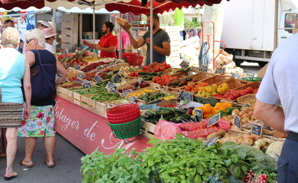 Vue du stand d'un producteur de fruits et légumes au marché provençal de Vaison-la-Romaine.