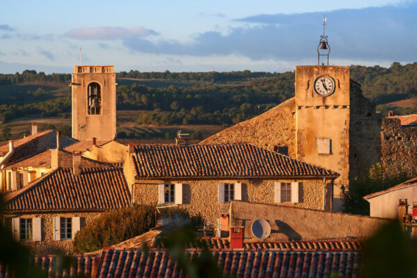 Vue de Buisson au soleil couchant avec clocher-tour et clocher de l'église.