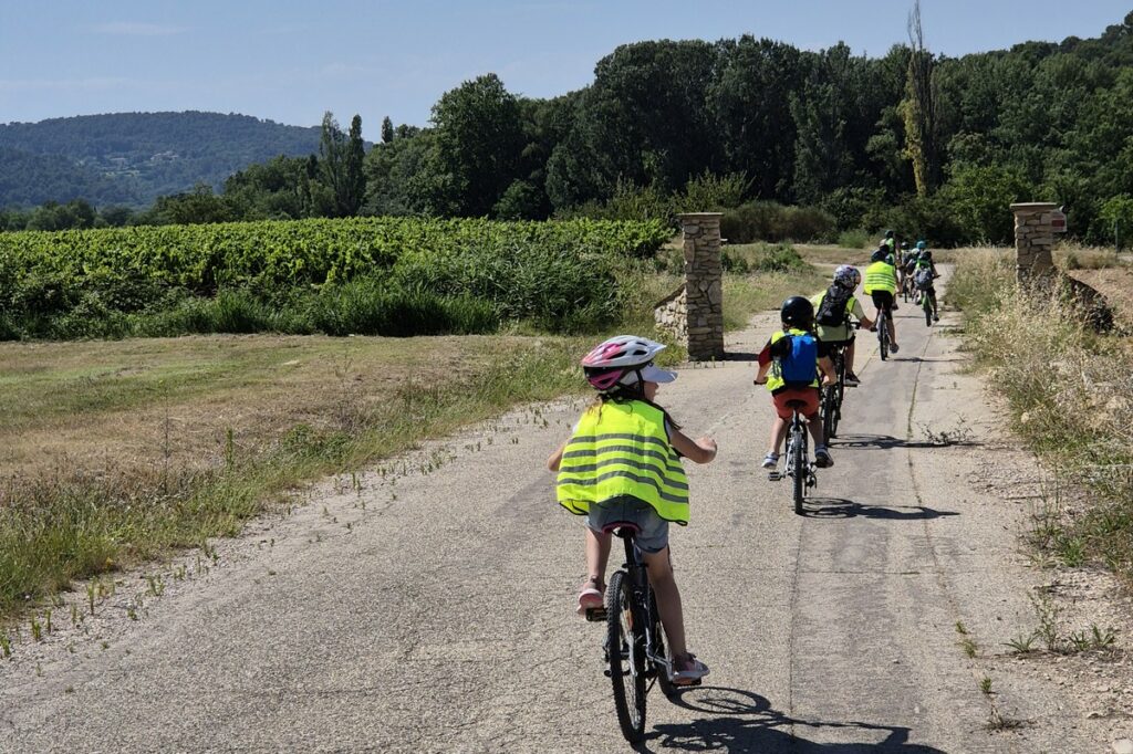 Des enfants font du vélo en file indienne sur un chemin.