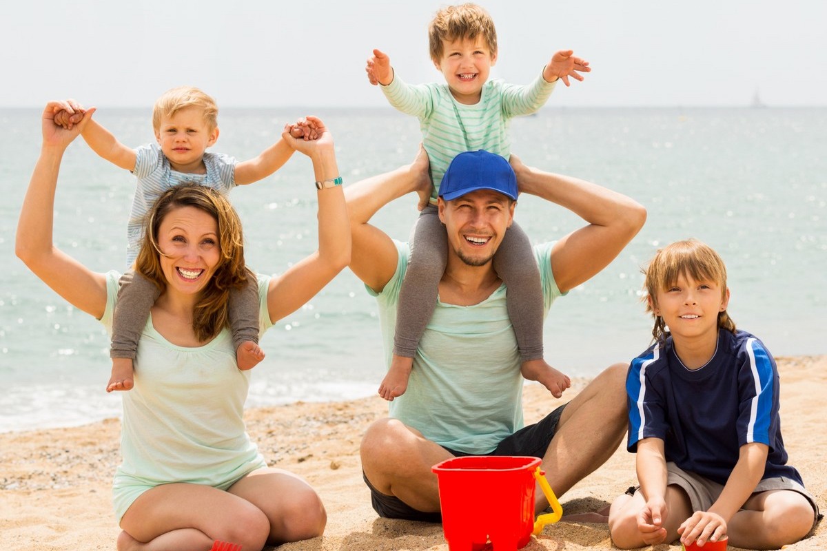 Happy family of five smiling at sea beach