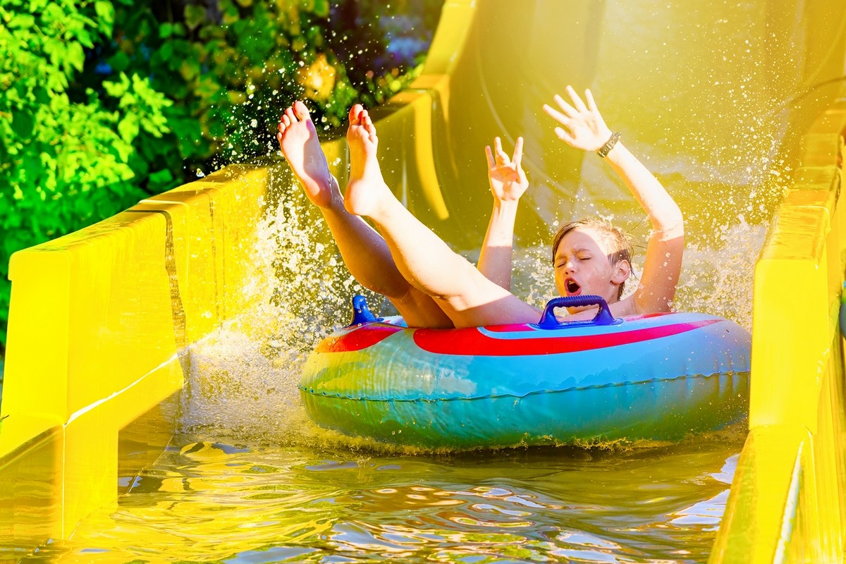 Boy having fun on yellow water slide at water park