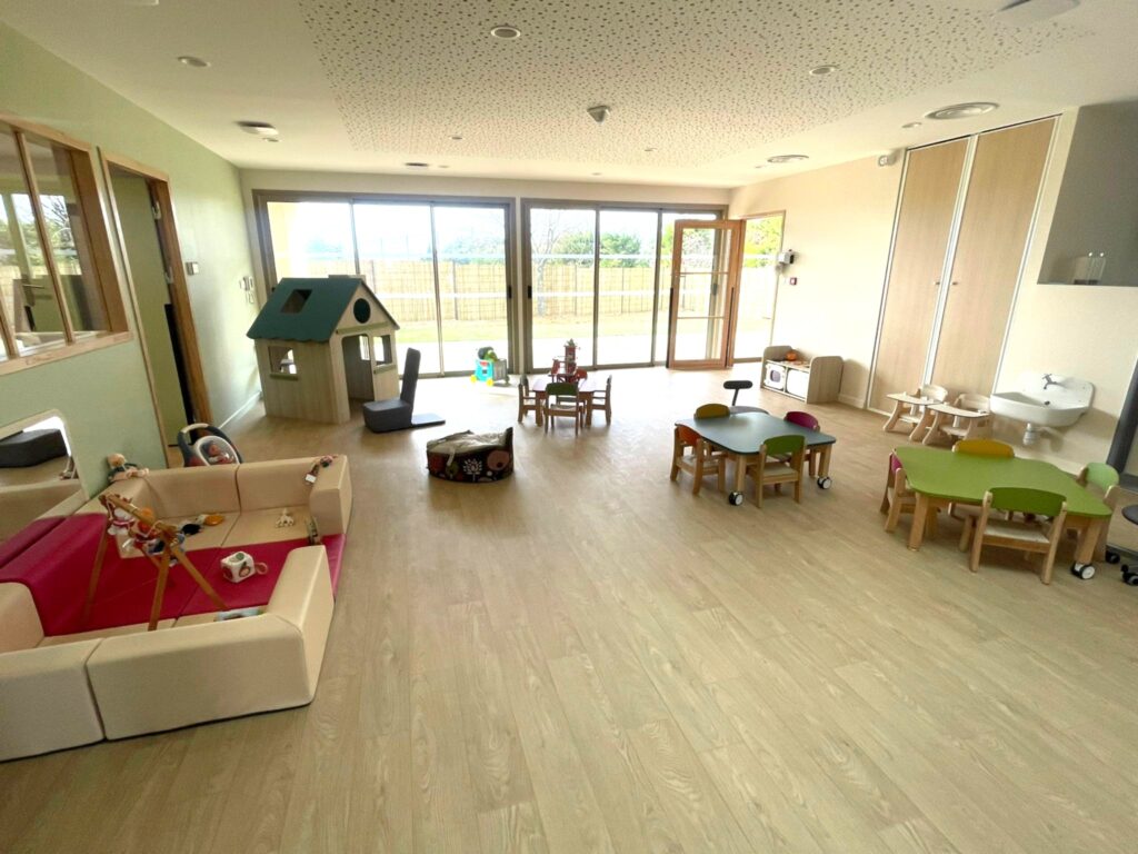 Salle principale de la micro-crèche intercommunale implantée à Rasteau. Vue sur le petit mobilier, les jeux et la grande baie vitrée qui donne sur le jardin.